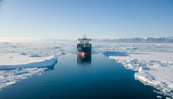 Современный контейнеровоз плывет по Северному морскому пути среди льдов в арктических водах.