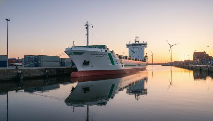 Новый альянс в Голландии: Seatrade стала акционером JR Shipping Современный фидерный контейнеровоз экологического класса стоит у чистого причала в порту Харлинген на рассвете.