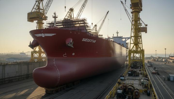 Nordic American Tankers обновляет флот: новые суда из Южной Кореи Огромный новый нефтяной танкер-суэцмакс в сухом доке судостроительной верфи в процессе строительства, окруженный портовыми кранами.